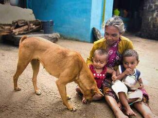 An Indian woman sits with her grandchildren and dog