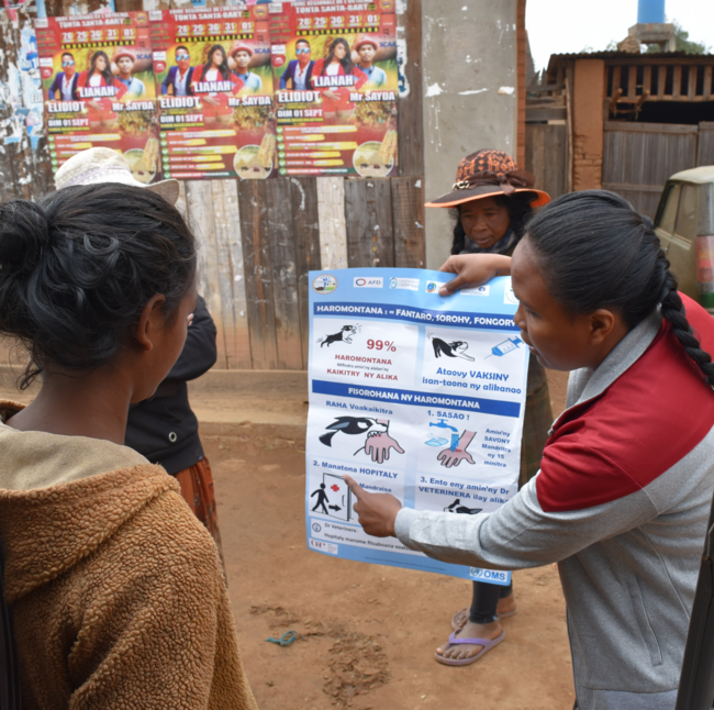 Educator showing a rabies prevention poster to women